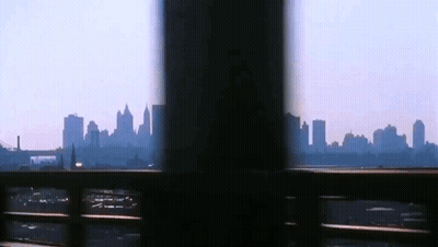 A View Of A City Skyline Through A Fence GIF