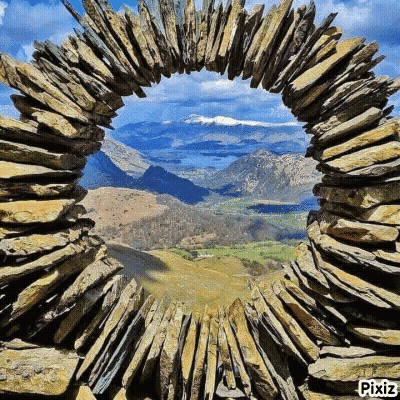 A View Of A Mountain Valley Through A Stone Arch GIF