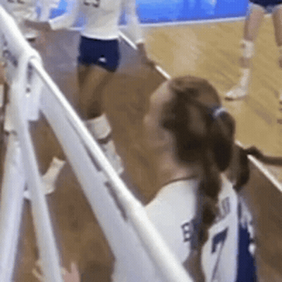 A Volleyball Player Wearing A White Jersey With The Number 7 On It Is Standing Next To A White Fence . GIF
