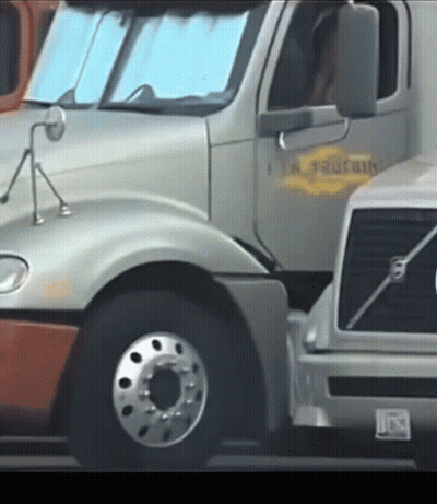 A Volvo Truck Is Parked Next To A Silver Truck GIF
