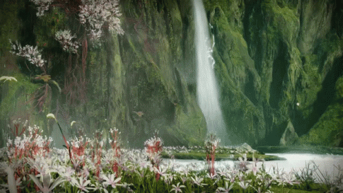 A Waterfall Is Surrounded By Flowers In A Lush Green Forest GIF
