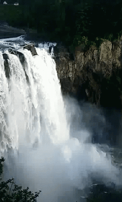 A Waterfall Is Surrounded By Trees And A Cliff GIF