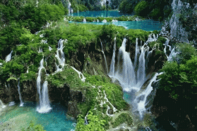 A Waterfall Is Surrounded By Trees And A Lake GIF
