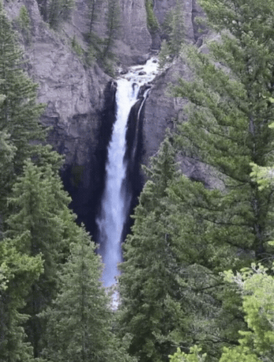 A Waterfall Is Surrounded By Trees And Cliffs GIF