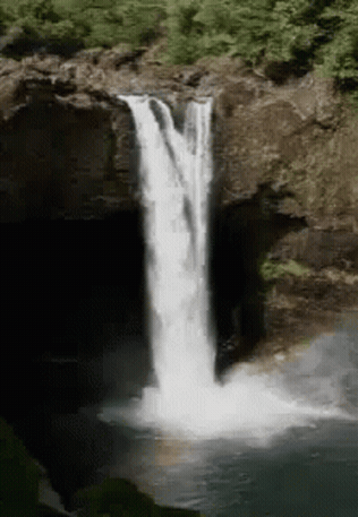 A Waterfall Is Surrounded By Trees And Rocks In The Woods GIF