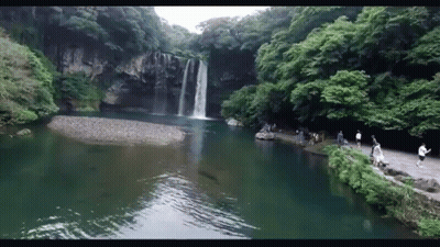 A Waterfall Surrounded By Trees And A Lake GIF