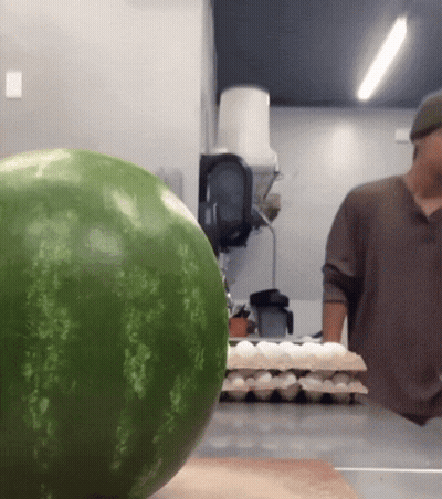 A Watermelon Sits On A Counter Next To A Man GIF