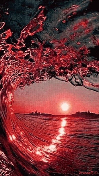 A Wave Is Breaking In The Ocean At Sunset And The Sun Is Reflected In The Water GIF