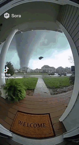 A Welcome Mat Is On The Porch Of A House With A Tornado Behind It GIF