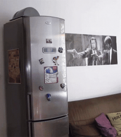 A Whirlpool Refrigerator With A Picture Of Pulp Fiction On The Wall Above It GIF