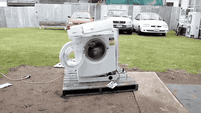 A Whirlpool Washing Machine Sits On A Wooden Pallet Outside GIF