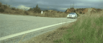 A White Bmw Is Driving Down A Road GIF