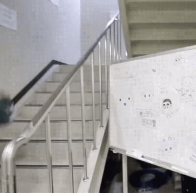 A White Board With Drawings On It Is Next To A Railing And Stairs GIF