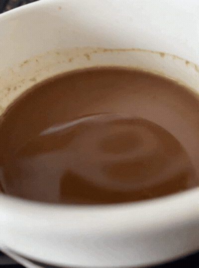 A White Bowl Filled With Brown Liquid With A Swirl In It GIF