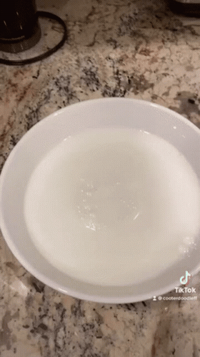 A White Bowl Filled With Water Is On A Counter Top . GIF