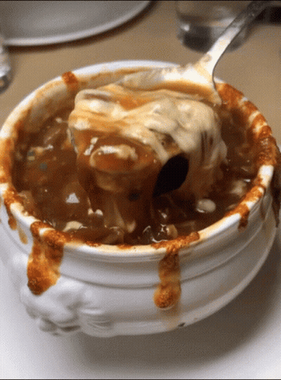 A White Bowl Of Soup With A Spoon In It GIF