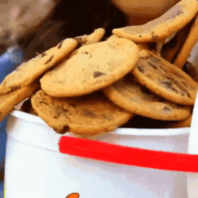 A White Bucket Filled With Chocolate Chip Cookies With A Red Handle GIF