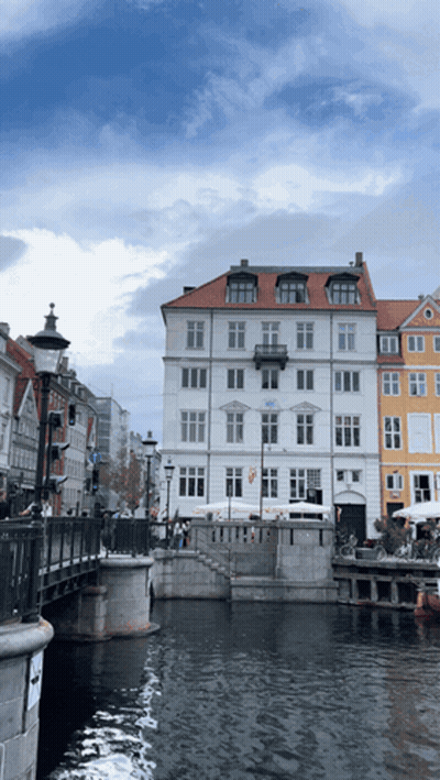 A White Building With A Red Roof Sits Next To A River GIF