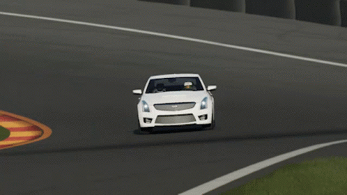 A White Cadillac Is Driving Down A Road GIF