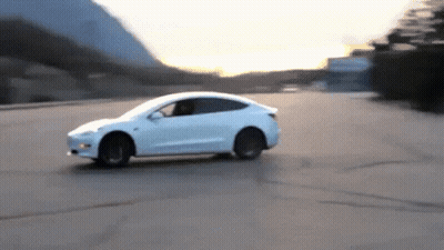 A White Car Driving Down A Road With Mountains In The Background GIF