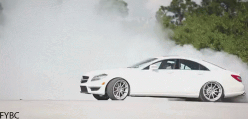 A White Car Is Drifting On A Road With Smoke Coming Out Of The Tire . GIF