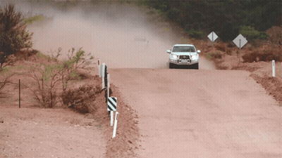A White Car Is Driving Down A Dirt Road With A Sign That Says ' A ' On It GIF