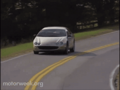 A White Car Is Driving Down A Road With Motorweek.org Written In The Corner GIF