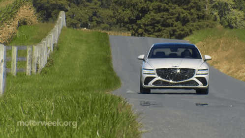 A White Car Is Driving Down A Road With Motorweek.org Written On The Bottom Right GIF