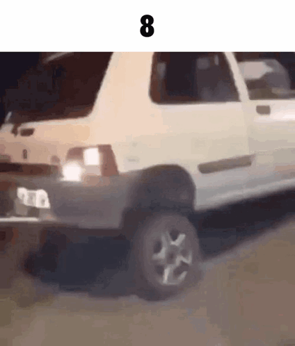 A White Car Is Driving Down A Road With The Number 8 On The Bottom Of It . GIF