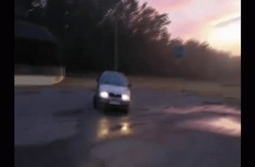 A White Car Is Driving Down A Road With Trees In The Background GIF