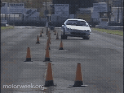 A White Car Is Driving Through A Row Of Orange Traffic Cones With Motorweek.org Written On The Bottom Right GIF