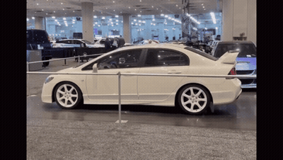 A White Car Is Parked Behind A Metal Barrier GIF