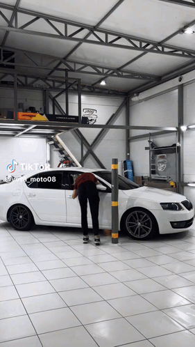 A White Car Is Parked In A Garage With A Tiktok Sticker GIF