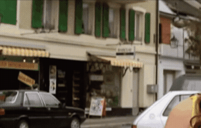 A White Car Is Parked In Front Of A Building That Has A Sign On It That Says ' A ' On It GIF
