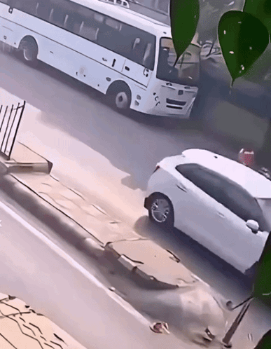 A White Car Is Parked On The Side Of The Road Next To A White Bus With The Letters Tb On The Front GIF