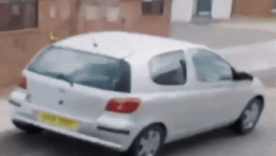 A White Car Is Parked On The Side Of The Road GIF