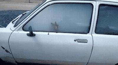 A White Car With A Hand Sticking Out Of Its Window GIF