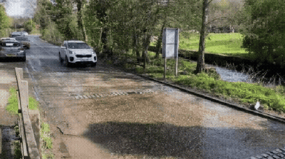 A White Car With A License Plate That Says ' Jcw ' On It Is Driving Down A Road GIF