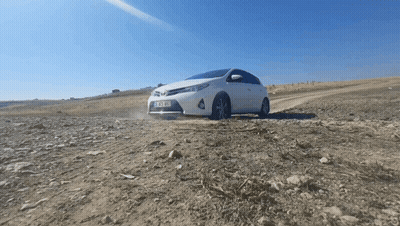 A White Car With A License Plate That Says ' Tk Xm ' On It Is Driving On A Dirt Road GIF