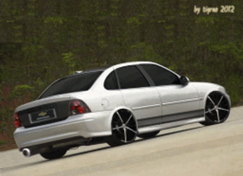 A White Car With Black Wheels Is Parked On The Road GIF