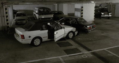 A White Car With The Door Open Is Parked In A Parking Lot GIF