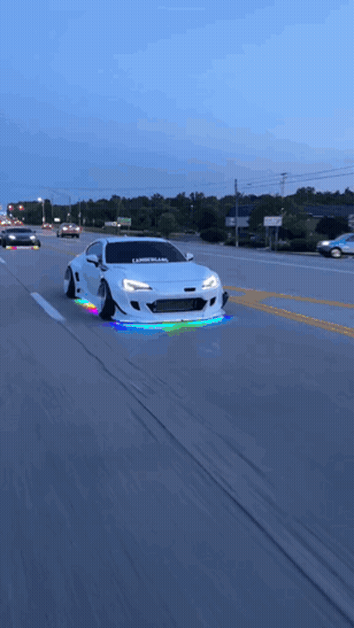 A White Car With The Word Libertyland On The Front Is Driving Down A Street GIF