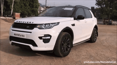 A White Discovery Is Parked On A Dirt Road GIF