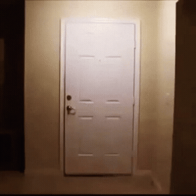 A White Door Is Open In A Hallway In A Dark Room . GIF