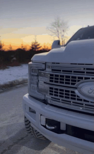 A White Ford Truck Is Parked In The Snow GIF