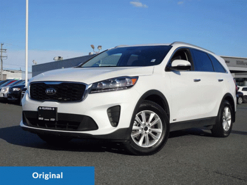 A White Kia Suv Is Displayed In Front Of A Dealership GIF