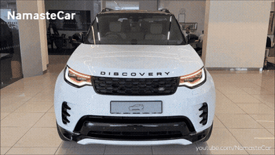 A White Land Rover Discovery Is Shown In A Showroom GIF
