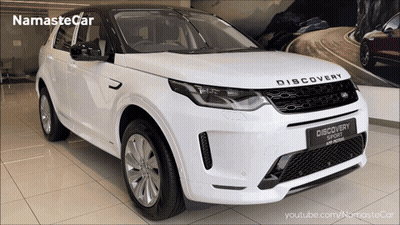 A White Land Rover Discovery Sport Is On Display In A Showroom GIF