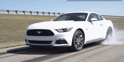 A White Mustang Is Driving Down A Road With Smoke Coming Out Of Its Tires GIF