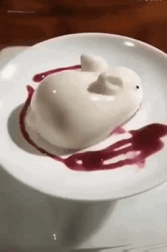 A White Plate Topped With A White Dessert In The Shape Of A Rabbit With Red Sauce . GIF